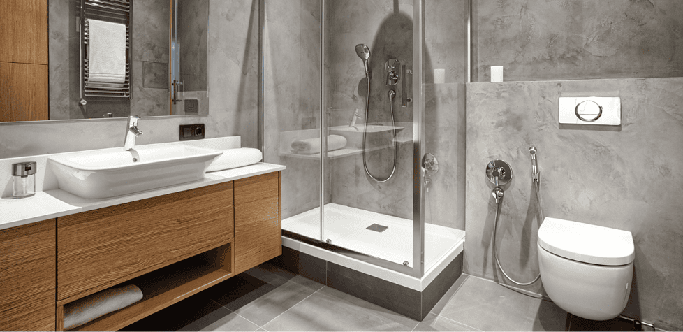 Ein modernes Badezimmer mit einer Dusche mit Glaskabine, einer wandmontierten Toilette, einem hölzernen Waschtisch mit Waschbecken sowie grau gefliesten Wänden und einem grau gefliesten Boden. Ein modernes Badezimmer mit einer Dusche mit Glaskabine, einer wandmontierten Toilette, einem hölzernen Waschtisch mit Waschbecken sowie grau gefliesten Wänden und einem grau gefliesten Boden.